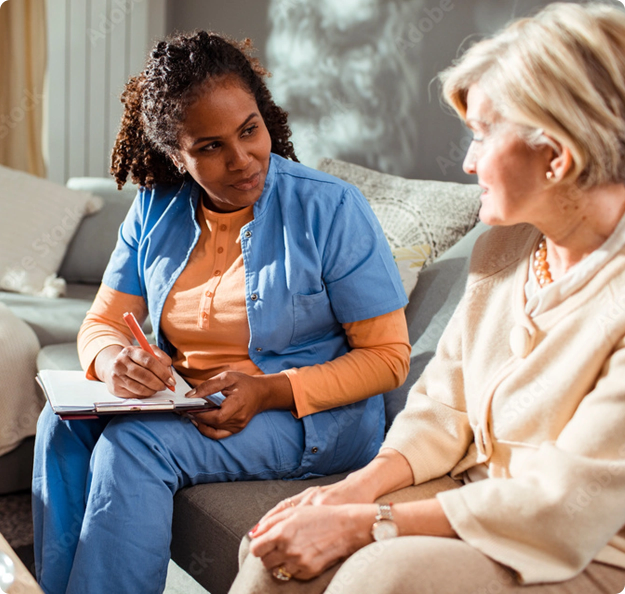 A nurse and an elderly patient laugh together.