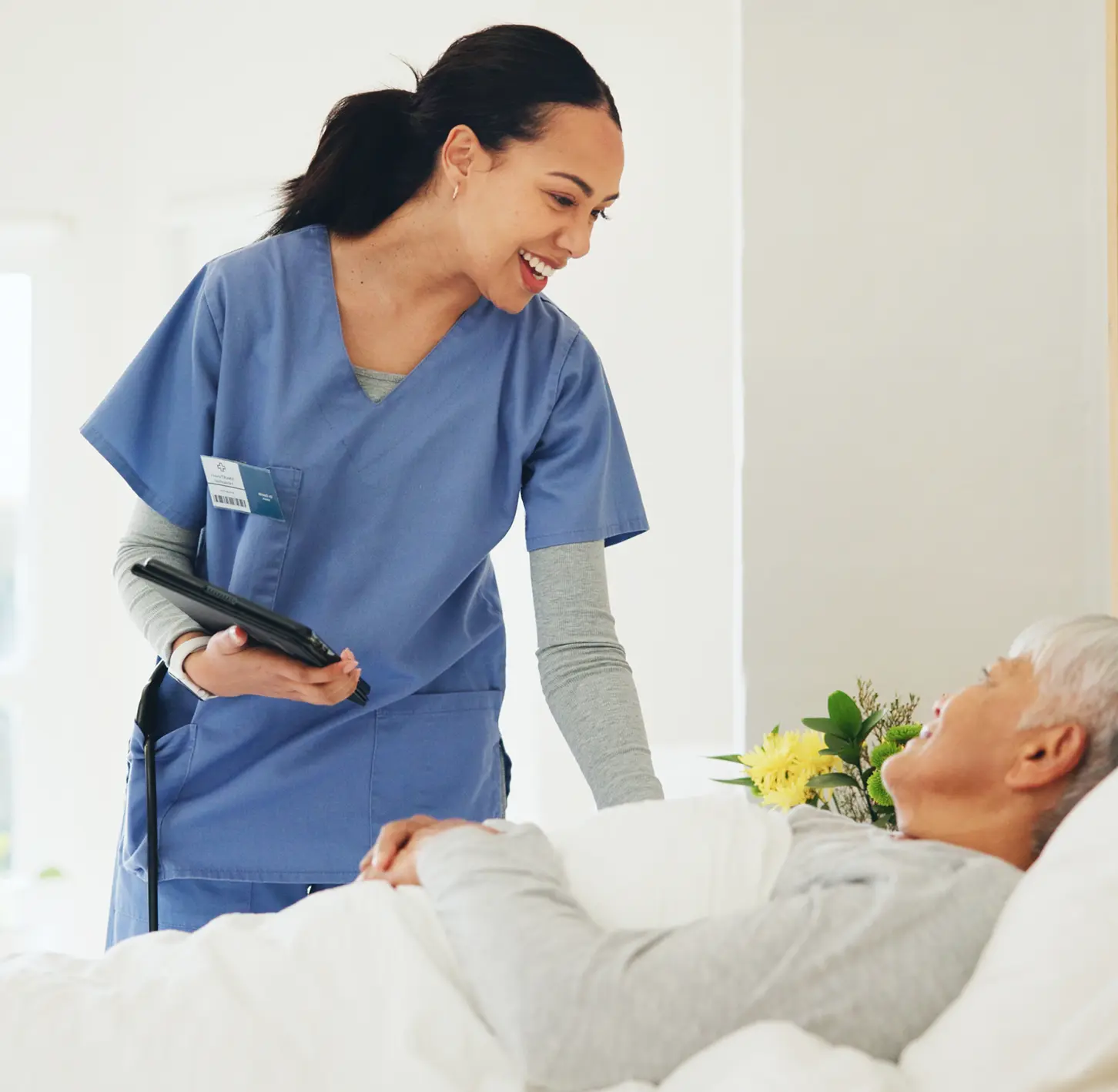 A female nurse helpfully addresses an elderly patient.