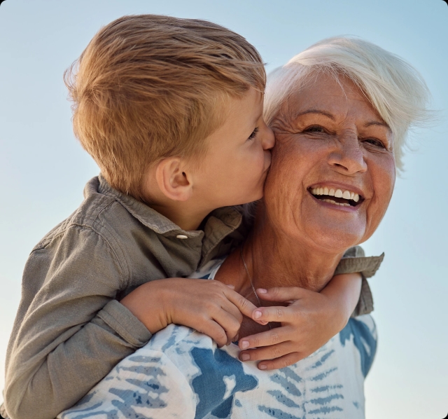 A young child kisses his grandmother on the cheek.